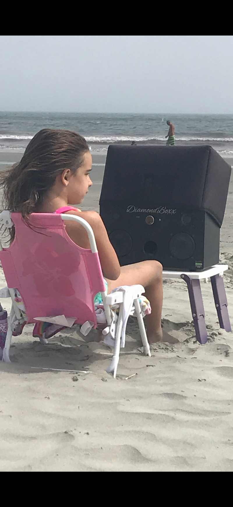A customer listening to a DiamondBoxx speaker at the beach.